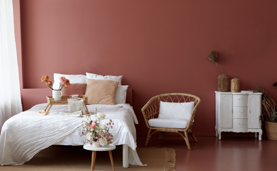 Cozy bedroom interior of retro armchair, vintage chest dwarf and bed on the background of the pink wall and painted wooden floor